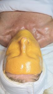 esthetician applying professional jelly mask during facial treatment